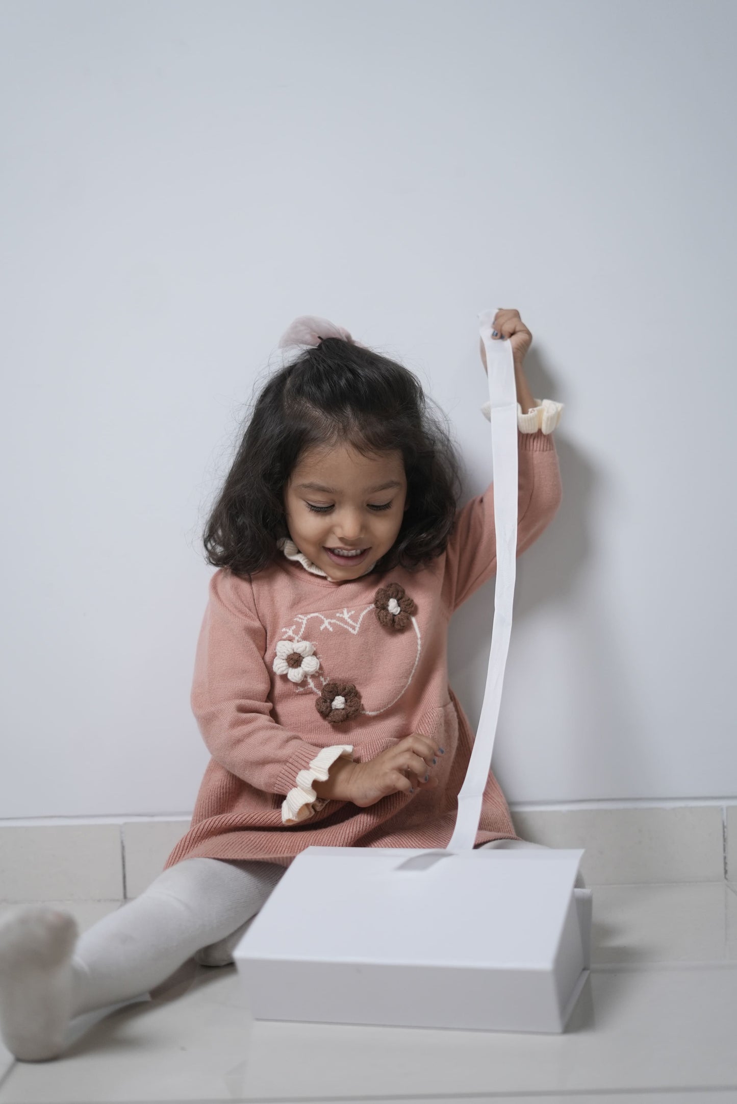 Child playing with a toy vacuum cleaner on a white floor.