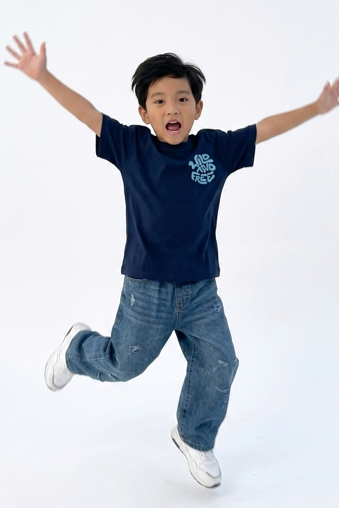 Child wearing a navy blue t-shirt and jeans with arms outstretched on a white background