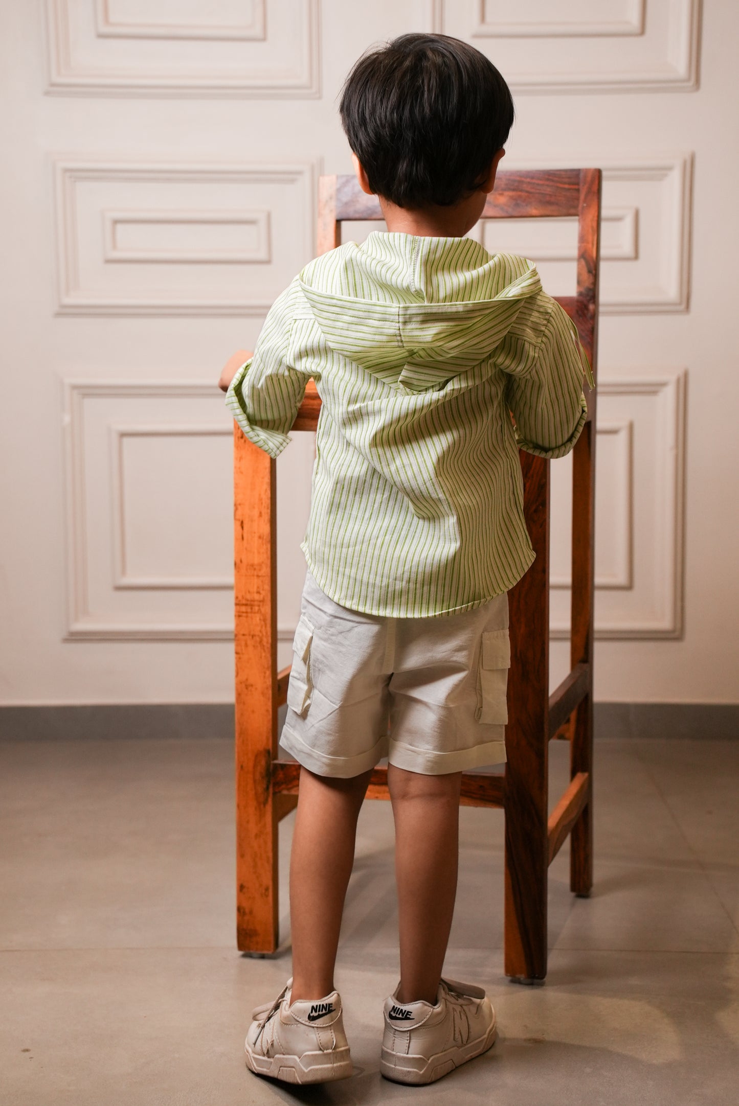 Child standing on a chair against a decorative wall.