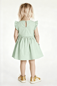 Child wearing a light green dress with ruffled sleeves on a white background