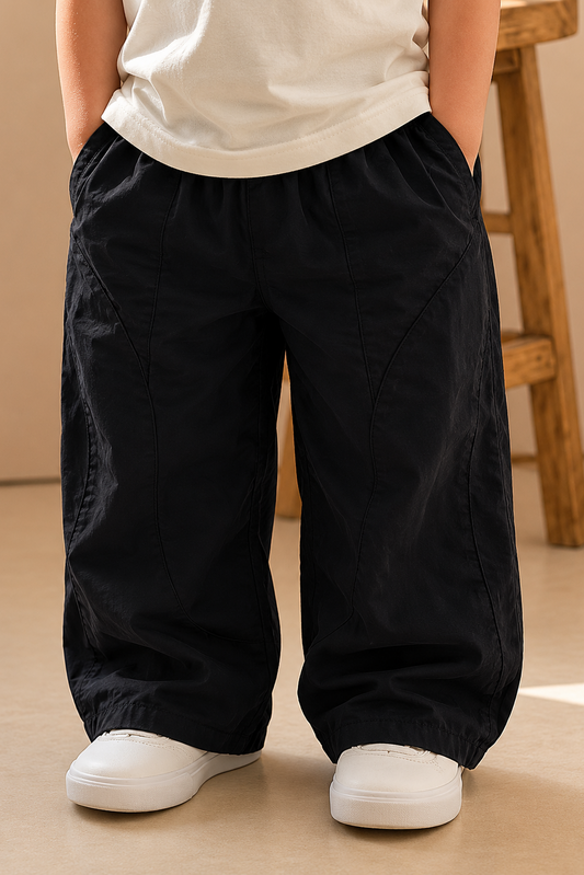 Person wearing black wide-leg pants and white shoes on a beige floor.