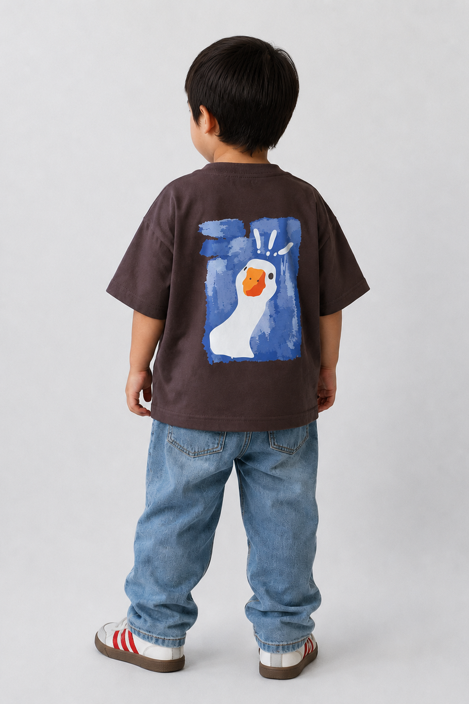 Child wearing a brown t-shirt with a colorful graphic on the back, standing against a plain background.