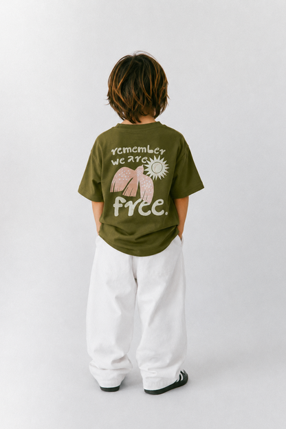 Child wearing a green t-shirt with a graphic and text, standing against a white background