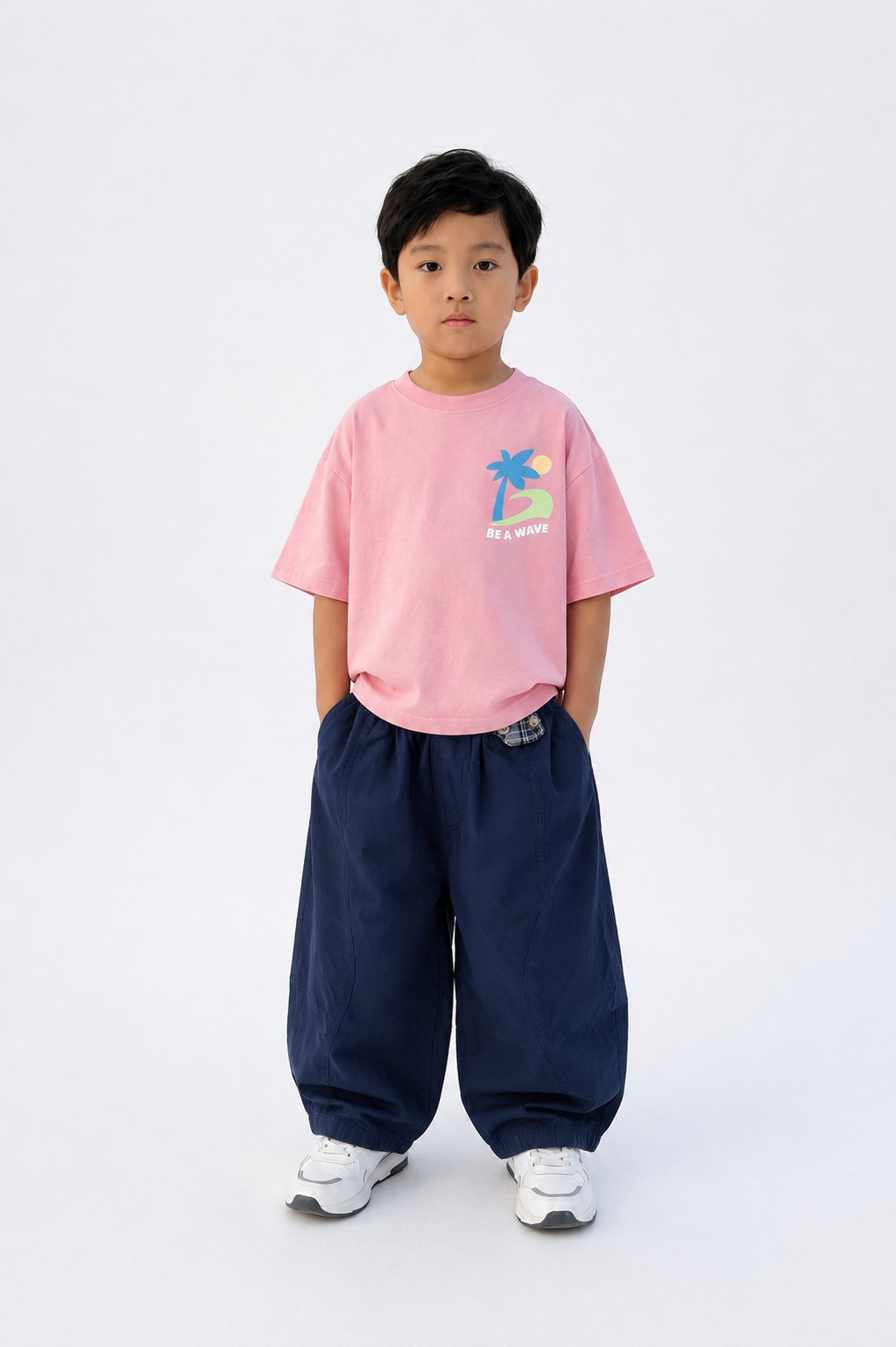 Child wearing a pink t-shirt with a graphic design and navy pants on a white background