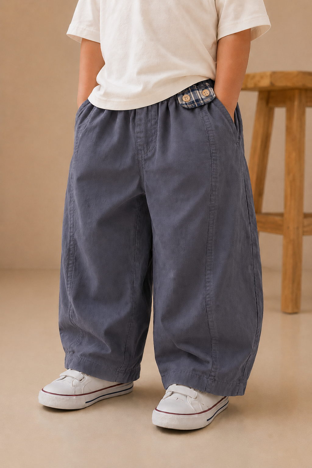 kid wearing blue wide-leg pants and white sneakers on a beige background