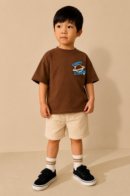 Child wearing a brown t-shirt with a graphic design on a beige background
