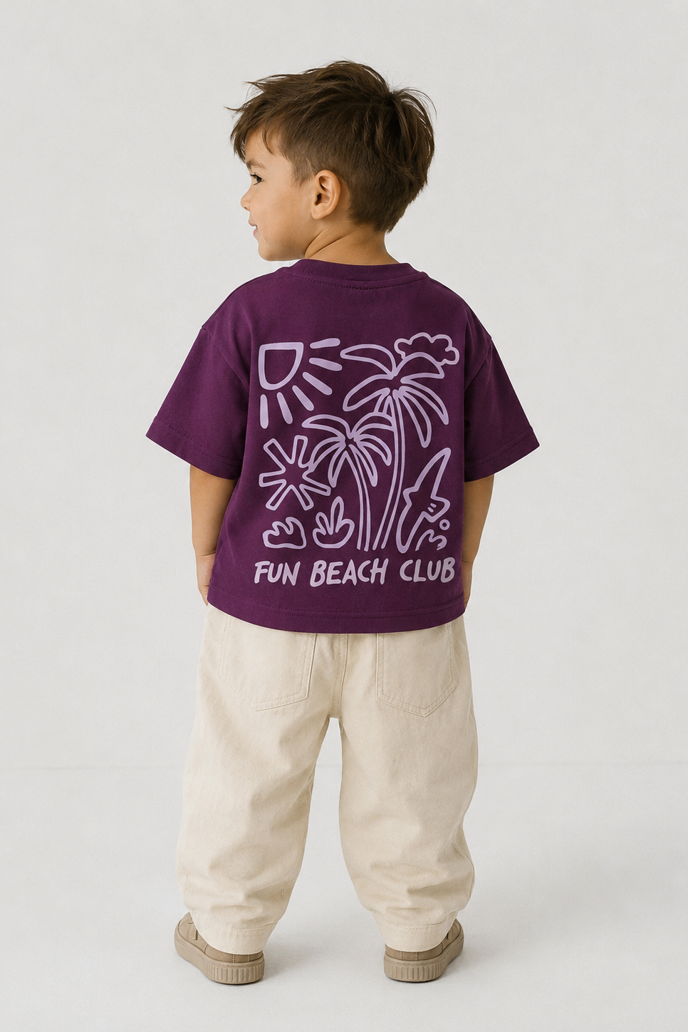 Child wearing a purple t-shirt with 'Fun Beach Club' design on the back, standing against a white background.