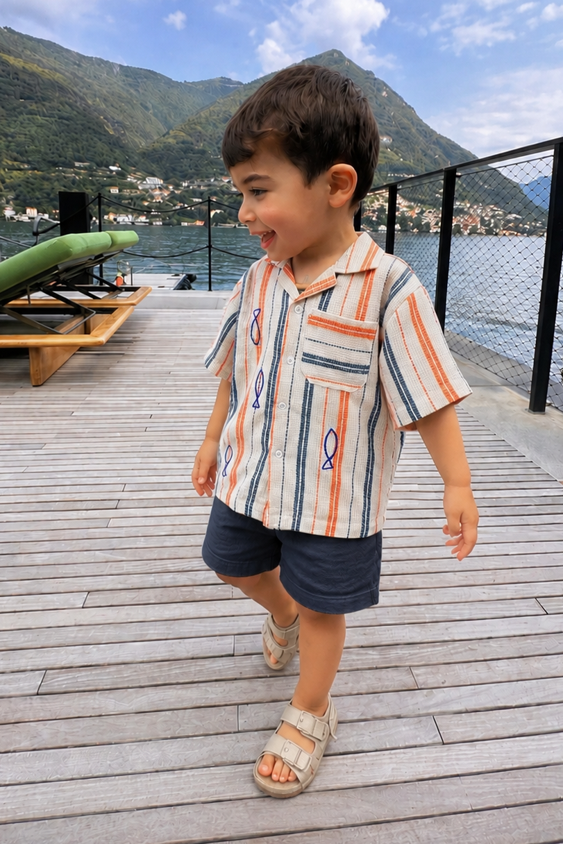 Child walking on a wooden deck by a waterfront with mountains in the background