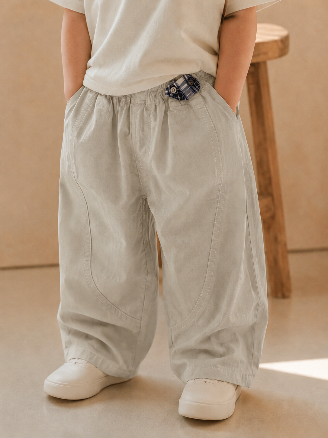Person wearing beige wide-leg pants and white shoes in a minimalistic setting