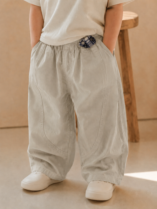 Person wearing beige wide-leg pants and white shoes in a minimalistic setting