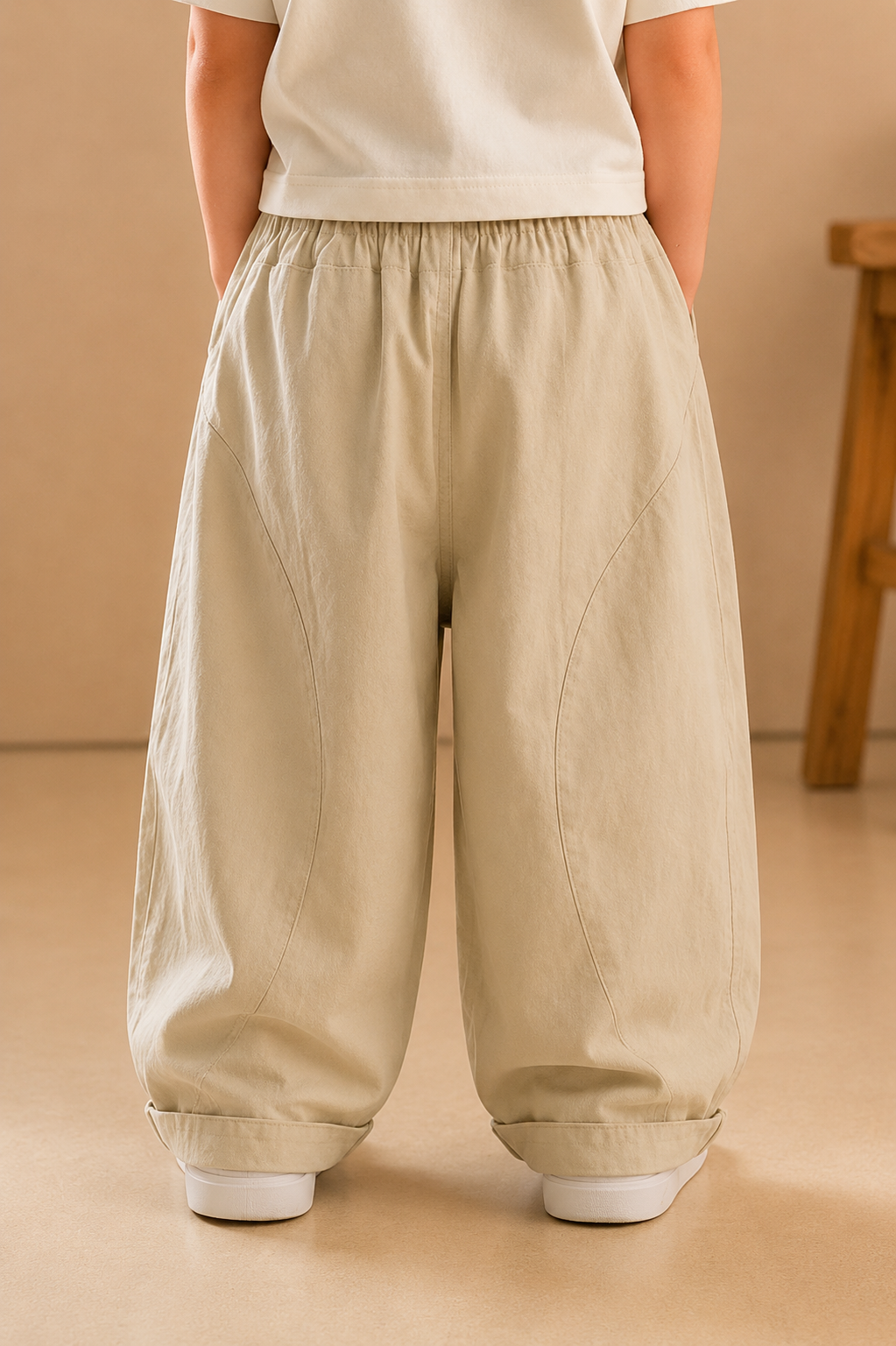Person wearing beige wide-leg pants on a beige background