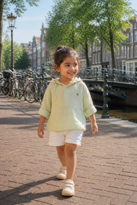 Child walking along a canal with bicycles and buildings in the background