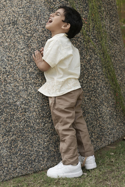 Child standing next to a large tree trunk in an outdoor setting