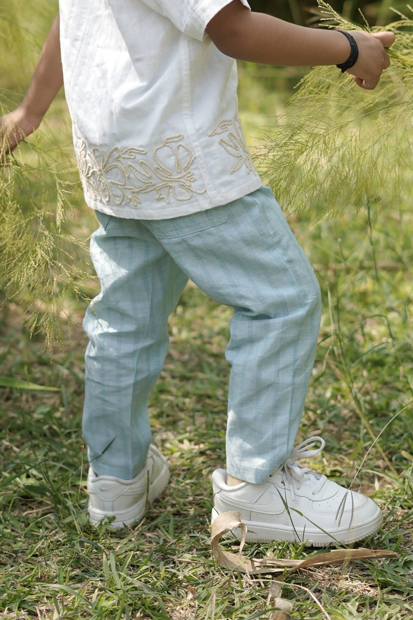 Child playing in a shallow water body with grass on the sides