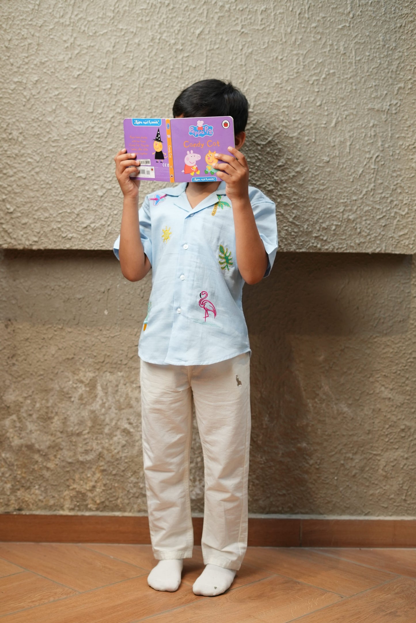 Child holding a colorful book in front of their face on a staircase.