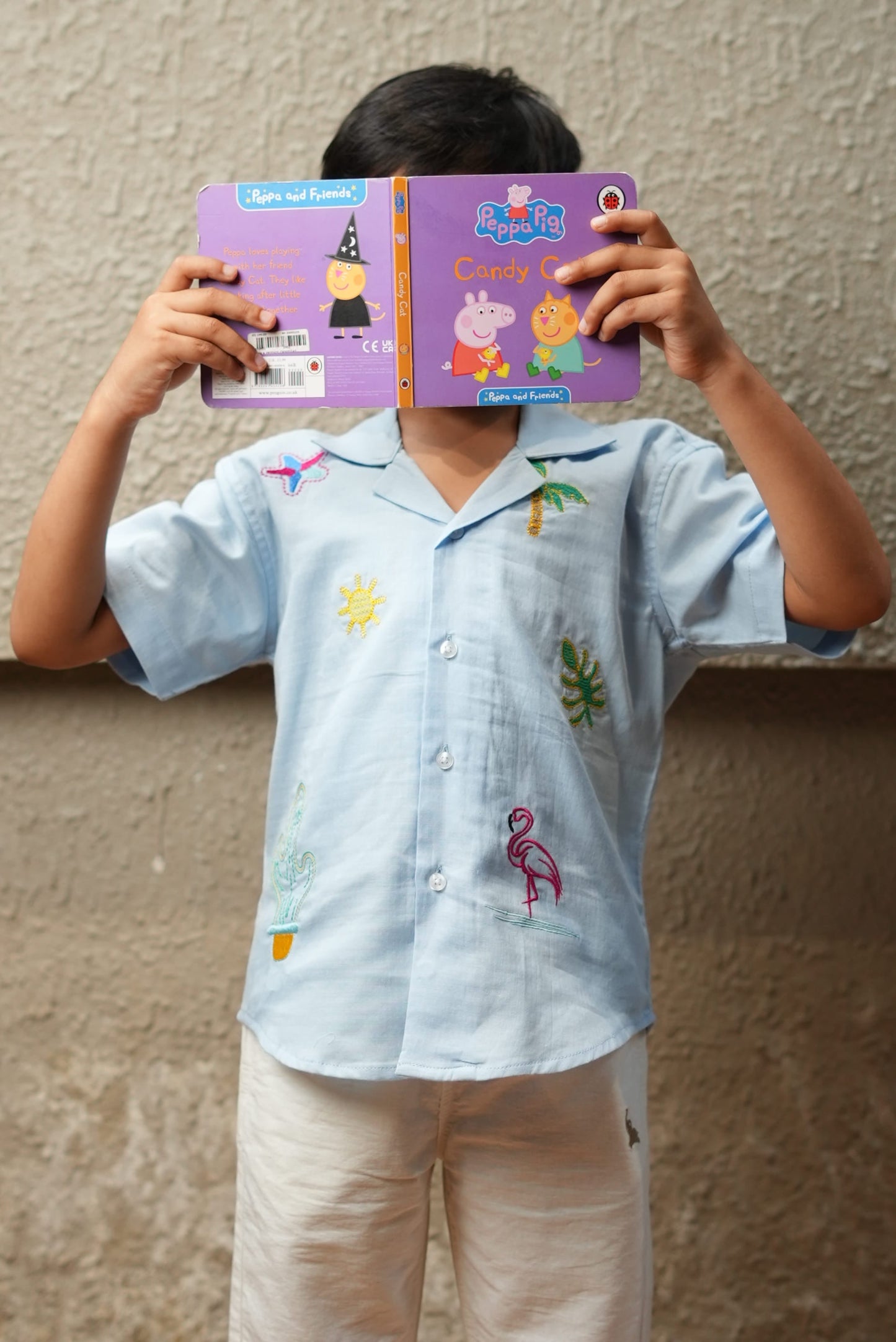 Child holding a colorful book against a plain background