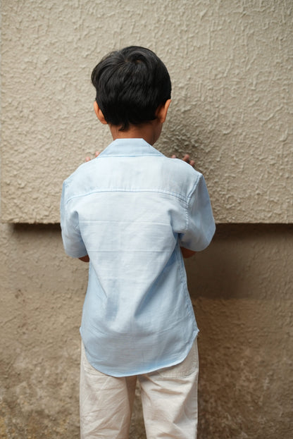 Person wearing a light blue shirt and beige pants standing on a carpeted floor.
