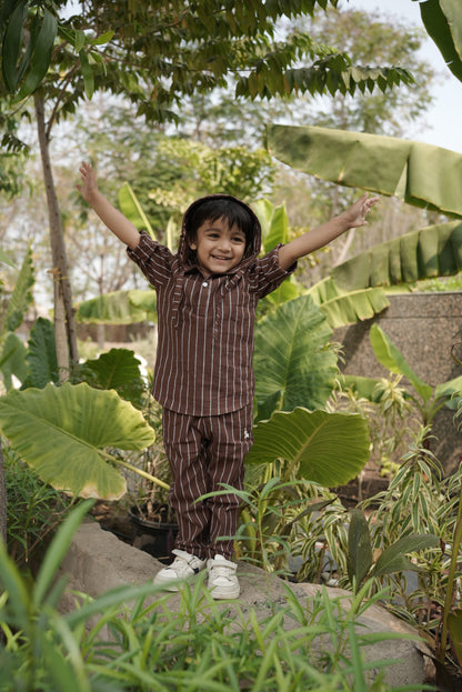 kid standing among large green leaves with a natural outdoor setting