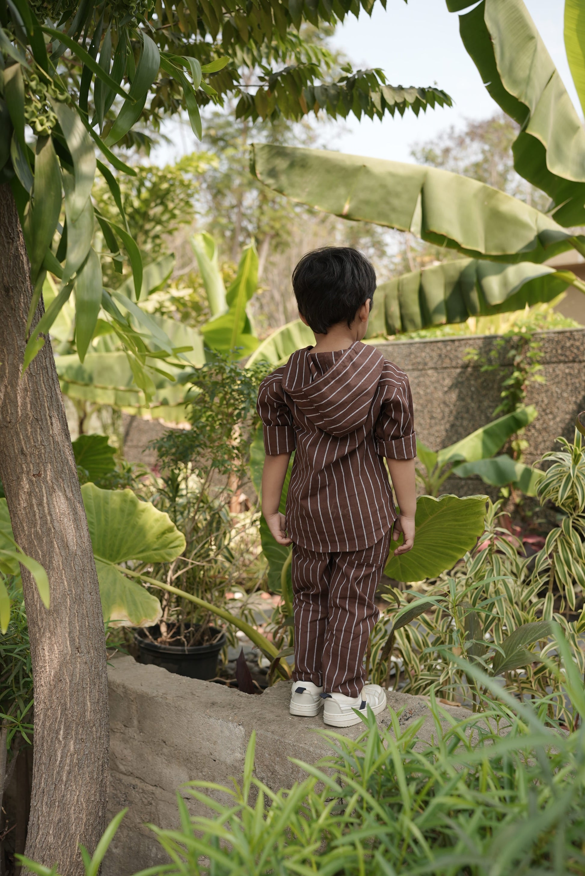 Person standing in a garden surrounded by green plants and trees
