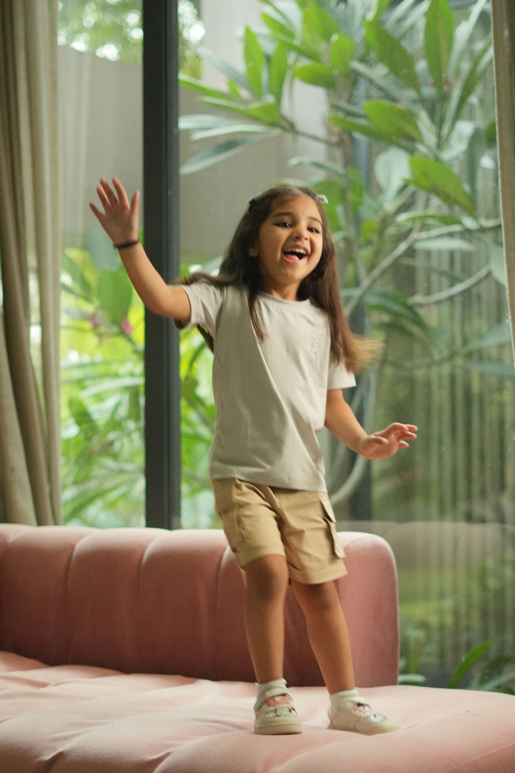 Person standing on a pink couch with a blurred green outdoor background
