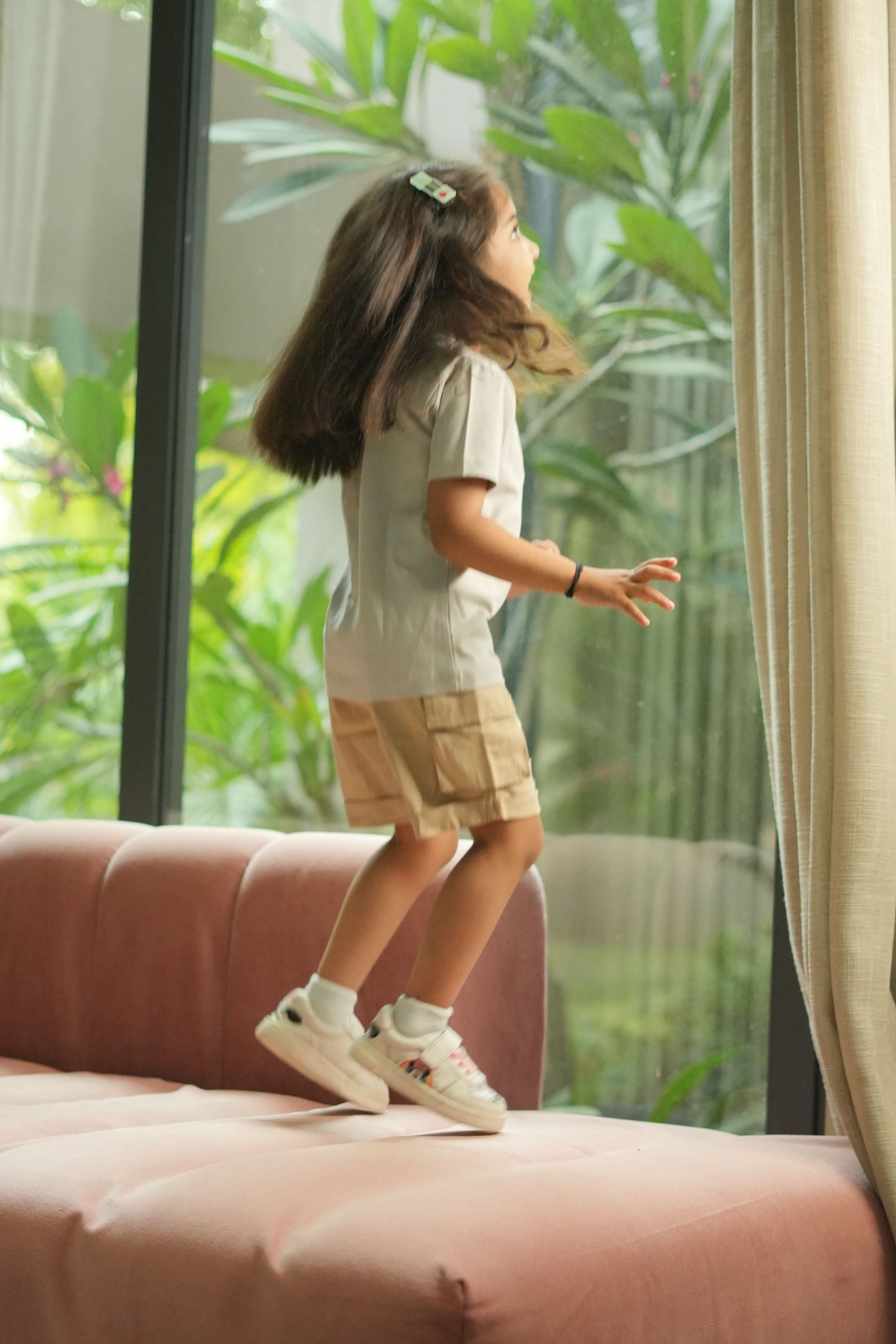 Child playing near a glass door with a view of greenery