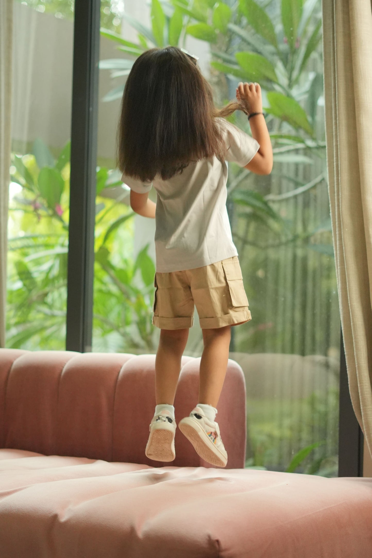 Person standing in a room with a large window and greenery outside