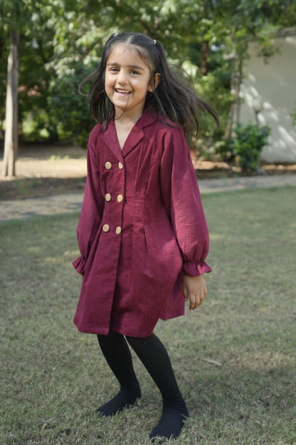 Young girl in a red coat standing outdoors with trees in the background