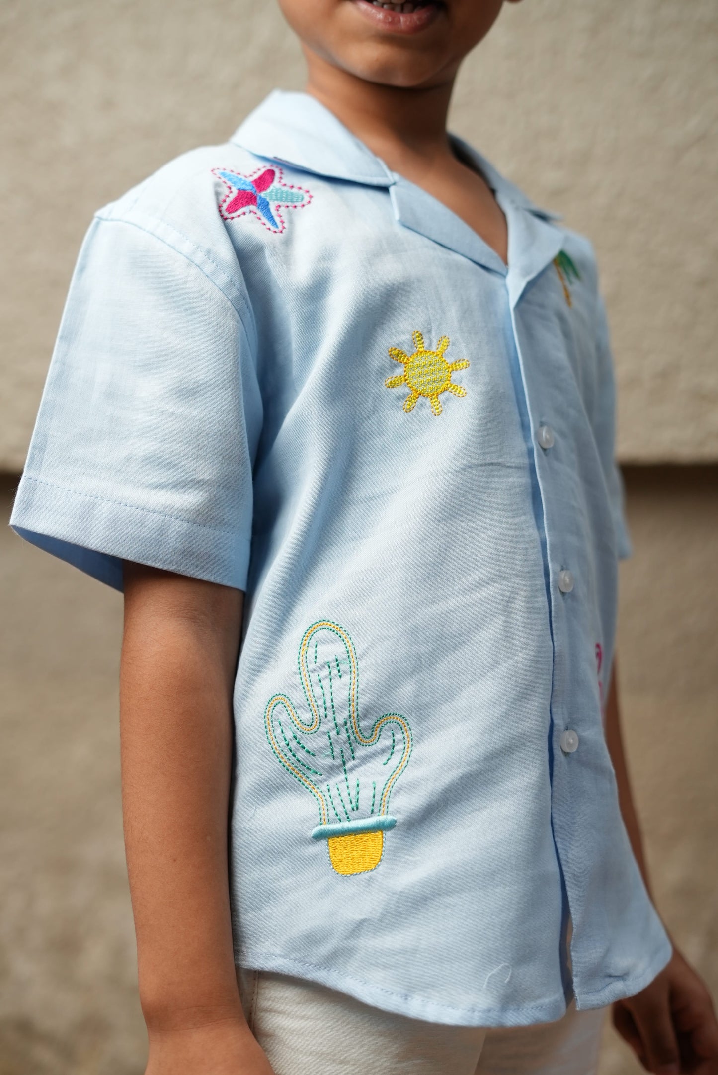 Light blue shirt with cactus and sun designs worn by a child