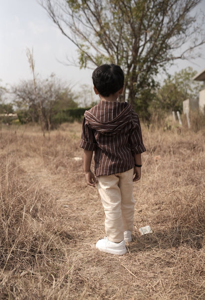 Child standing in a dry field with trees in the background