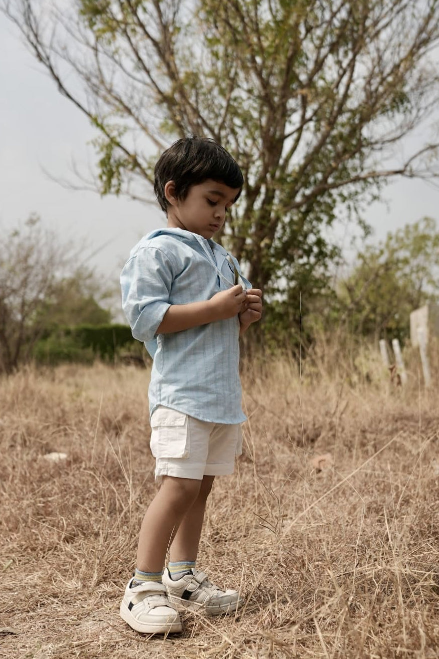 Child standing in a dry field holding a plant