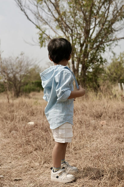 Child standing in a dry field with trees in the background
