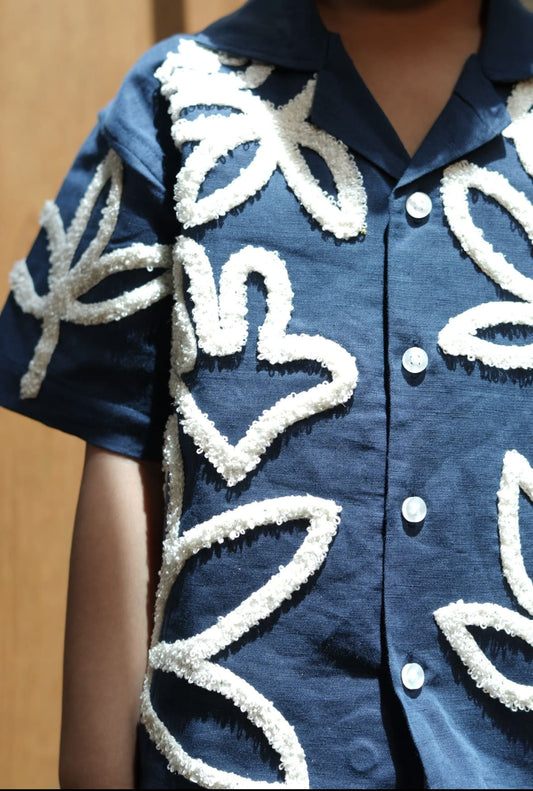 Blue shirt with white leaf patterns on a wooden background