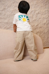 Person wearing a white shirt with a colorful design on a beige carpet