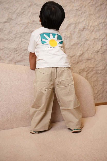 Person wearing a white shirt with a colorful design on a beige carpet