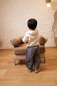 Person standing in a room with a wooden floor and beige sofa.