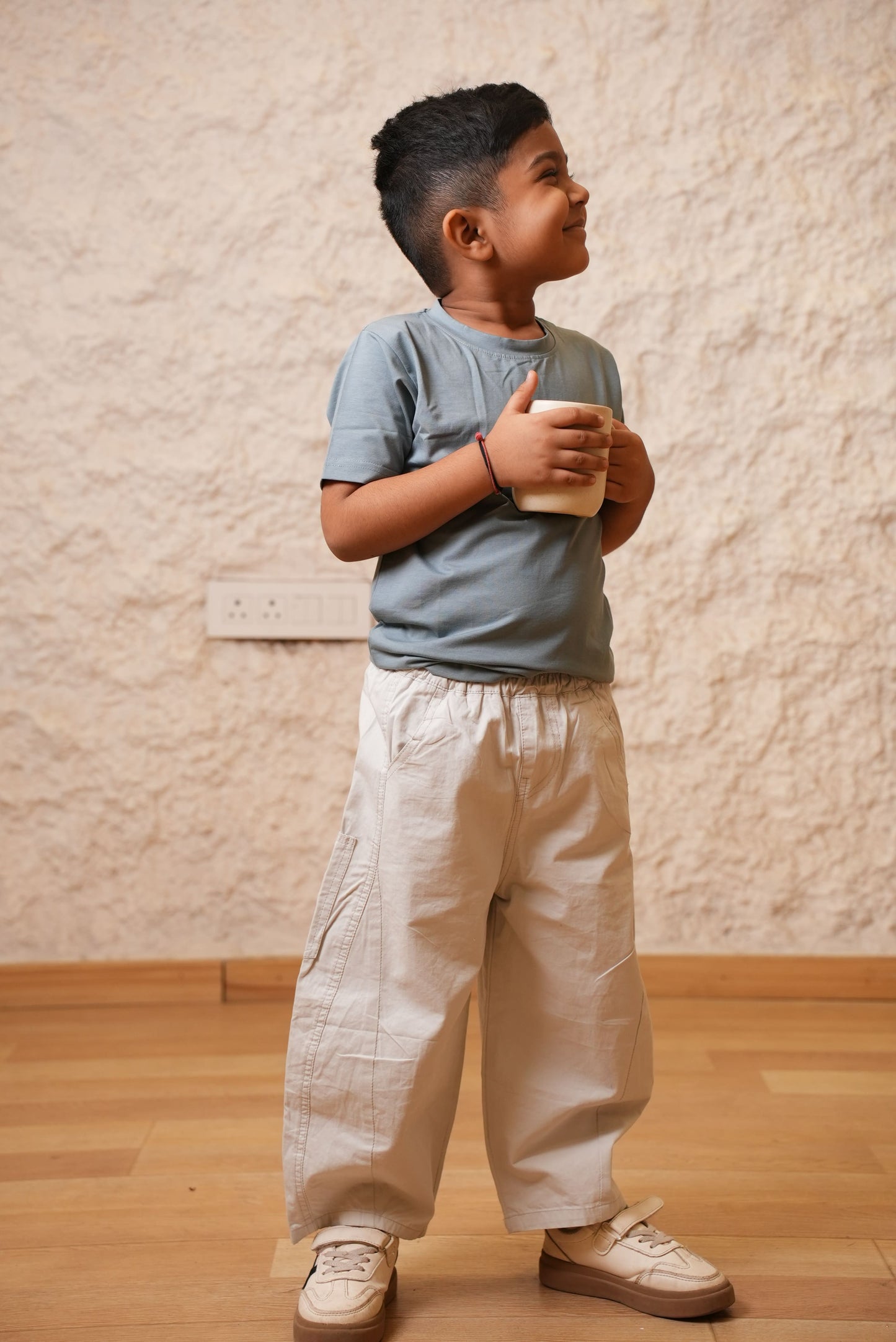 Person wearing a light blue shirt and beige pants on a wooden floor.