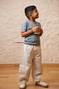 Person wearing a light blue shirt and beige pants on a wooden floor.