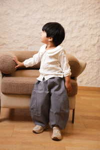 Person sitting on a couch holding a textured ball in a room with wooden floor and beige walls.
