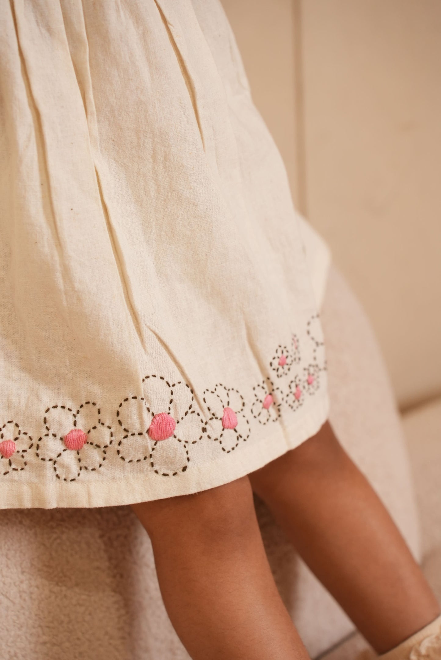 Close-up of a beige garment with floral embroidery on a neutral background