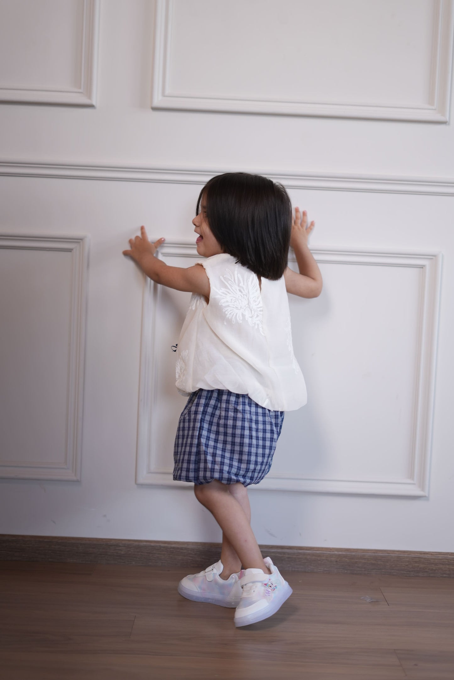 Person taking a mirror selfie in a room with white walls and wooden floor.