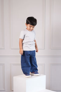 Child standing in a room with white furniture and wooden floor.
