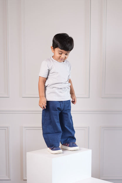 Child standing in a room with white furniture and wooden floor.
