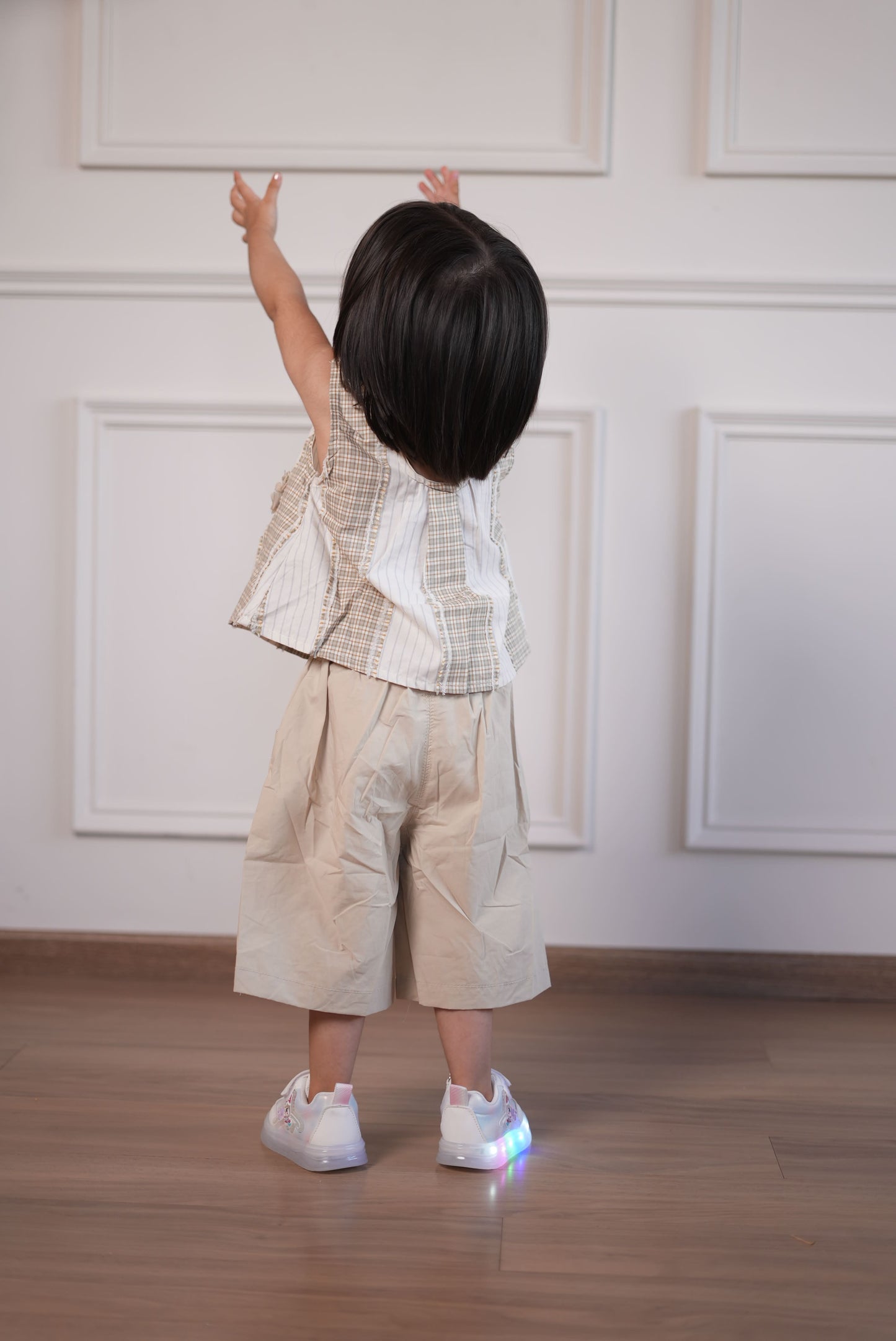 Person wearing a beige dress with white lace details in a minimal indoor setting.