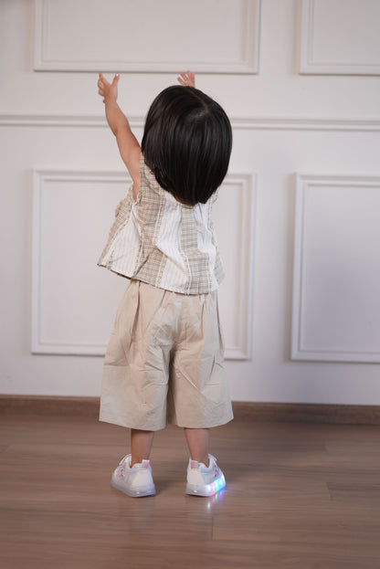 Person wearing a beige dress with white lace details in a minimal indoor setting.