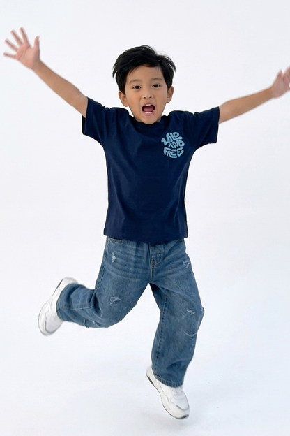 Child wearing a navy blue t-shirt and jeans with arms outstretched on a white background