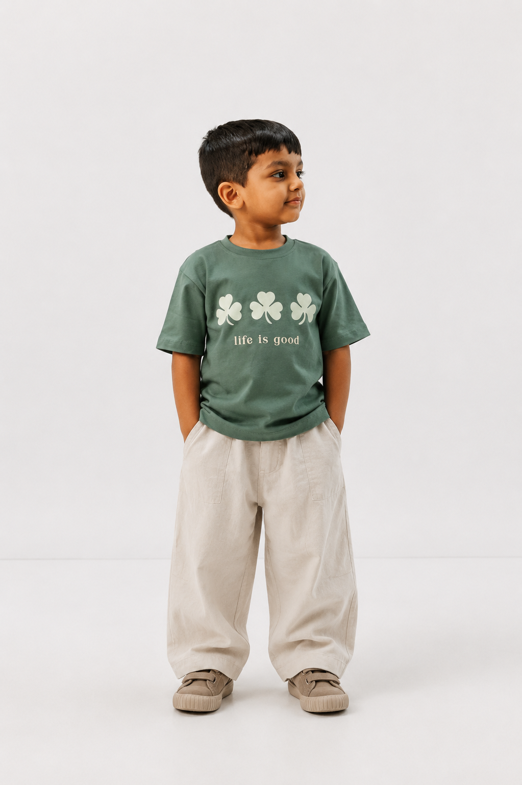 Child wearing a green 'life is good' t-shirt with shamrock design on a white background