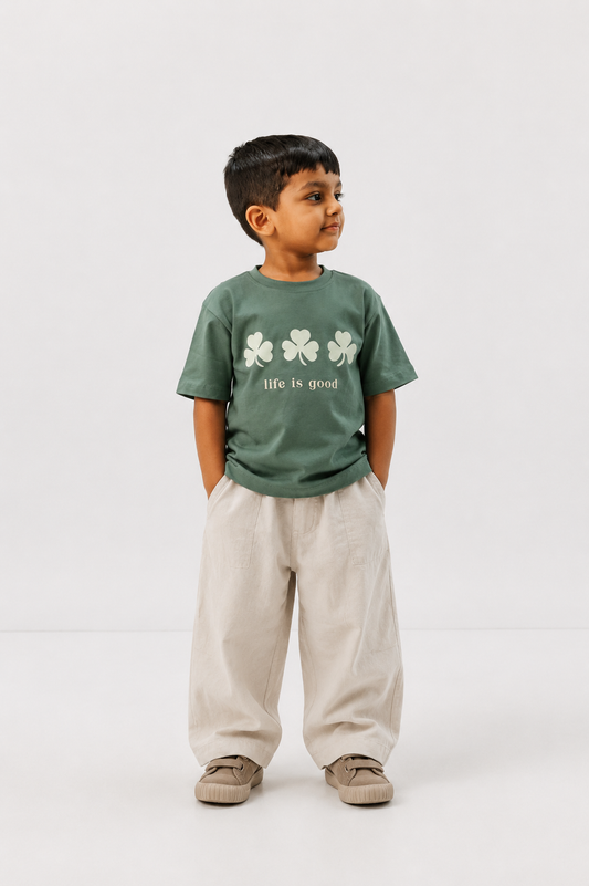 Child wearing a green 'life is good' t-shirt with shamrock design on a white background