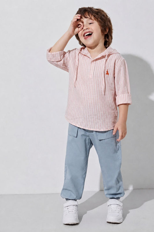Child wearing a pink striped shirt and blue pants, standing against a white background
