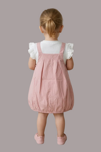Child wearing a pink dress standing on a tiled floor