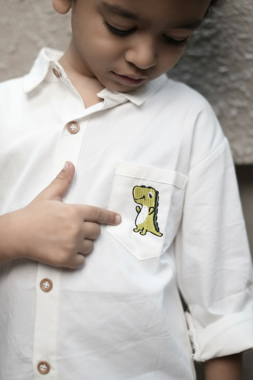 Child wearing a white shirt with a small pocket featuring a yellow dinosaur design.